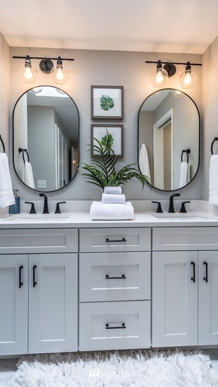 a bathroom with double sinks and two mirrors on the wall next to eachother