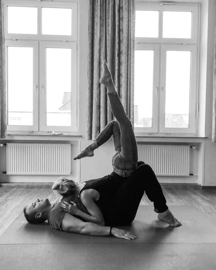 two people are doing yoga on the floor in front of a window and one person is upside down