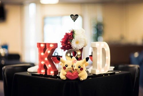 a table topped with two pokemon figurines next to a lighted letter and flower arrangement