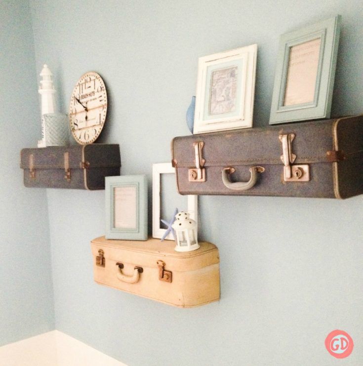 two suitcases are hanging on the wall above a shelf with pictures and framed photos