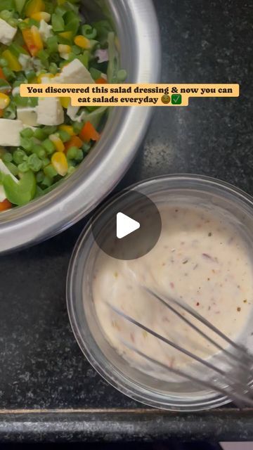 a bowl filled with salad next to a metal container full of dressing and a whisk