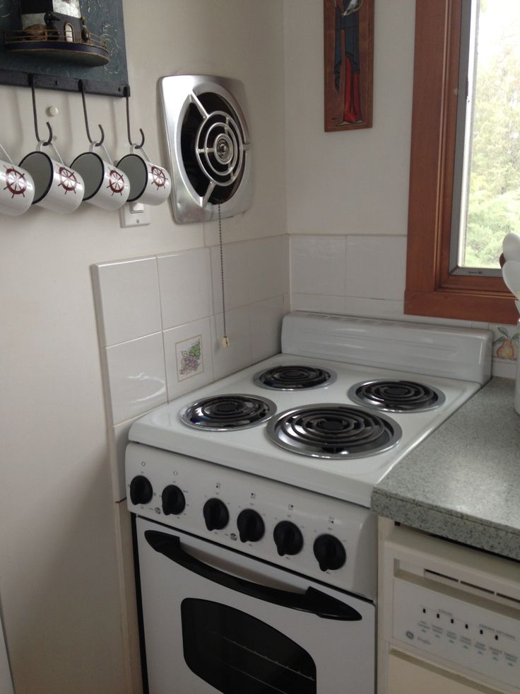 a white stove top oven sitting inside of a kitchen next to a counter with utensils on it