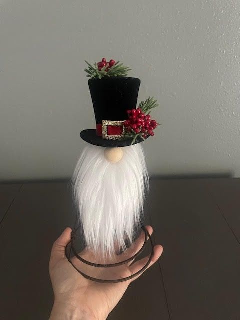 a hand is holding a fake white beard with a top hat on it's head