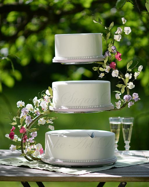 three tiered wedding cake with flowers on top and two glasses next to each other