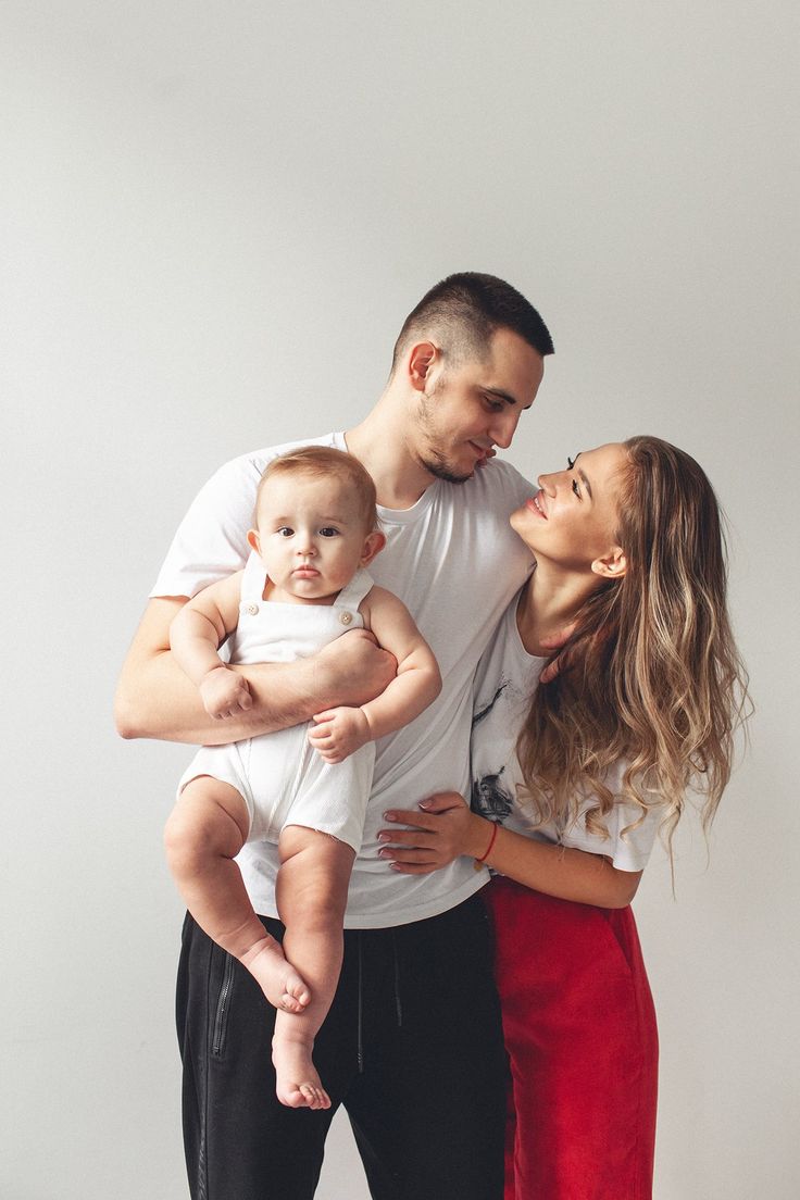 a man and woman holding a baby in their arms