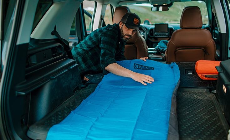 a man in the back of a van with a sleeping bag