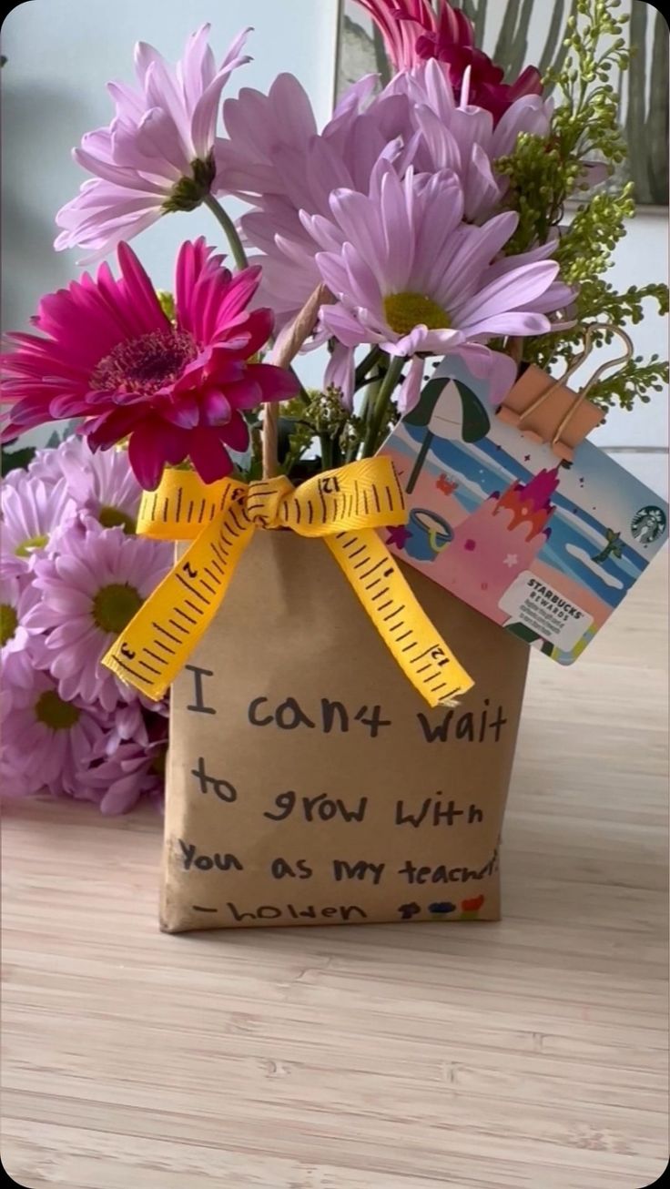 flowers in a paper bag with a message written on the front and side, sitting on a table