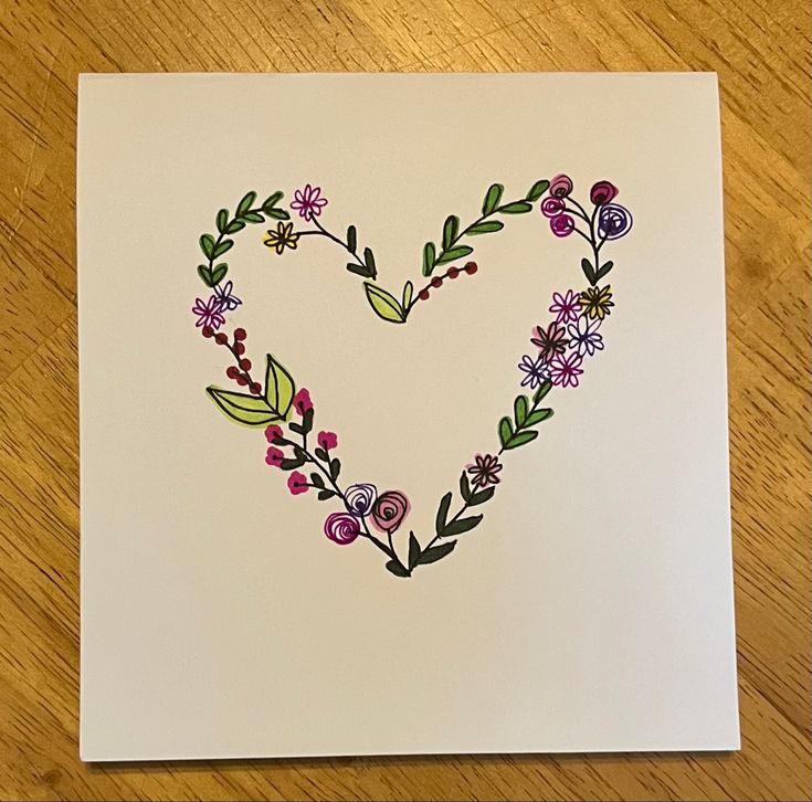 a heart made out of flowers and leaves on a white card with the word love written in it