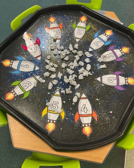 a black tray topped with lots of space themed magnets on top of a wooden table