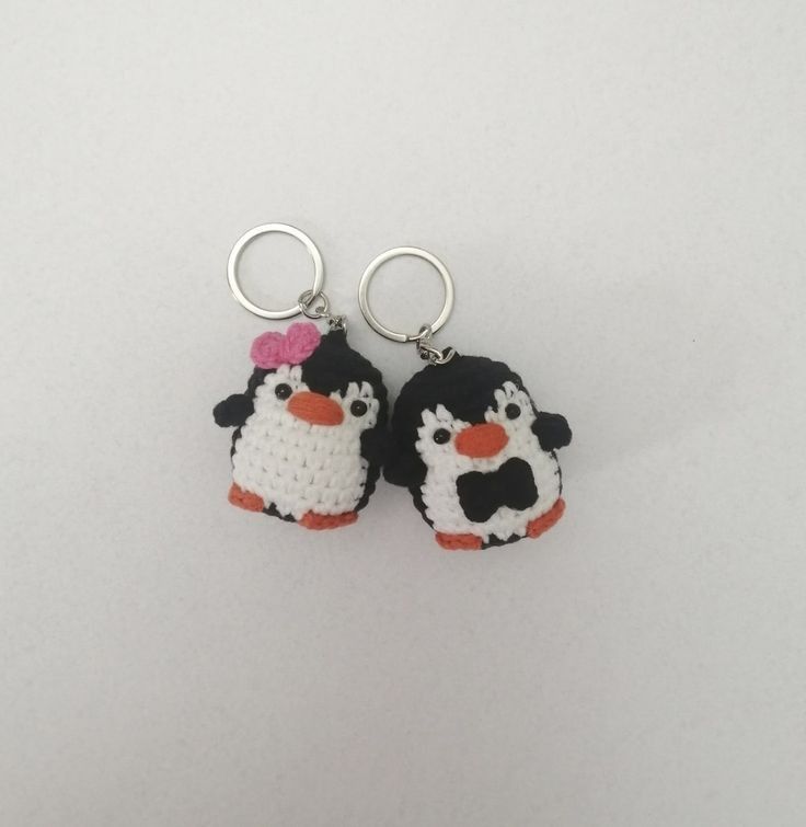 two small penguin keychains are shown on a white surface