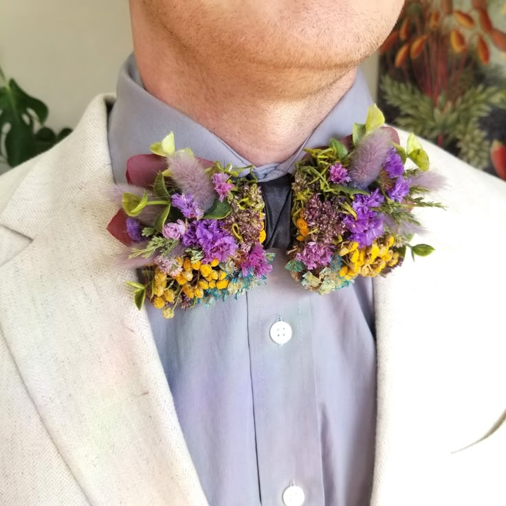 a man wearing a white suit and purple flowers on his lapel flower collar tie