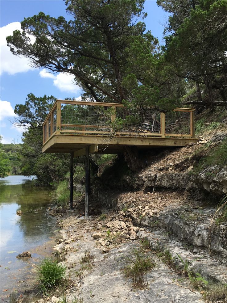 a wooden bridge over a river next to a forest