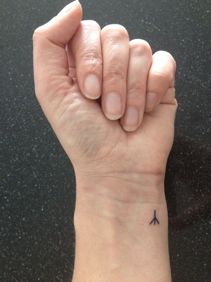 a woman's arm with a small airplane tattoo on the left side of her wrist