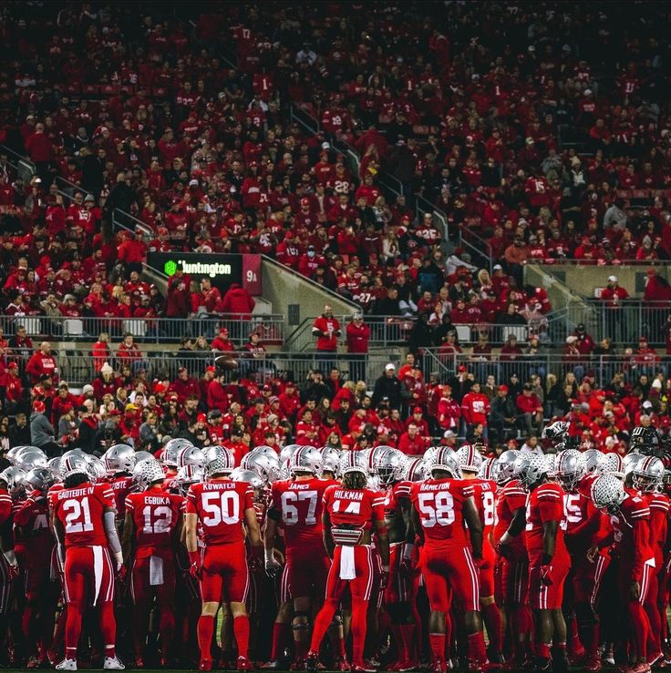 a group of football players standing on top of a field in front of an audience