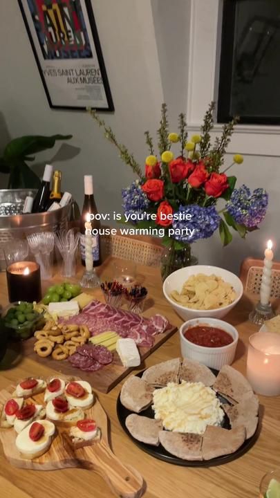 a wooden table topped with lots of food and drinks next to vases filled with flowers