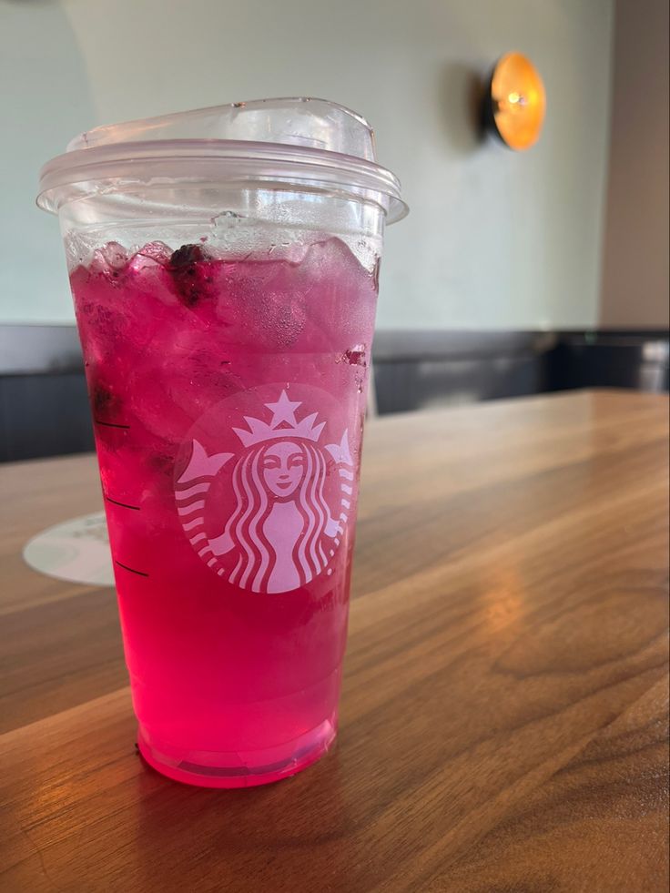 a pink drink sitting on top of a wooden table