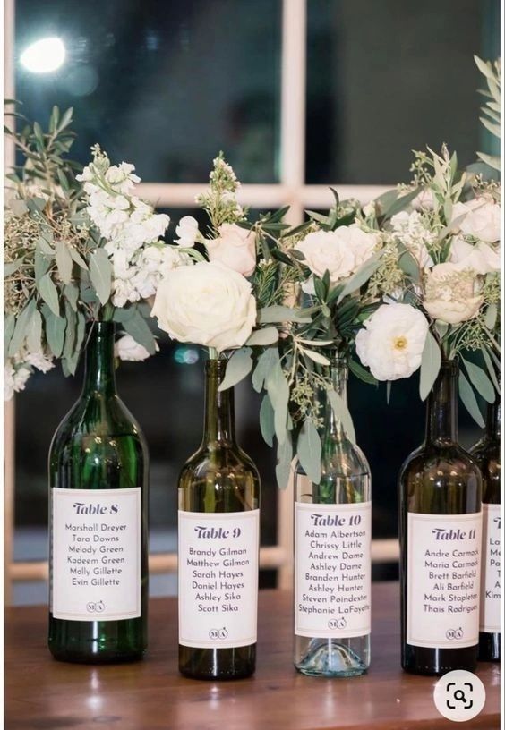 three wine bottles with flowers in them sitting on a table