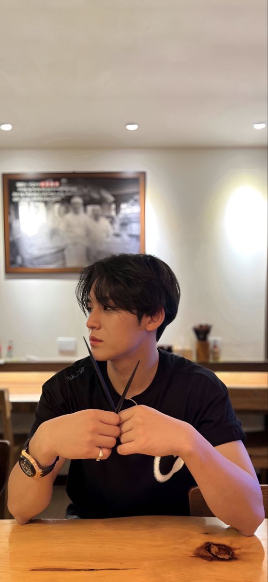 a young man sitting at a table with his hands folded