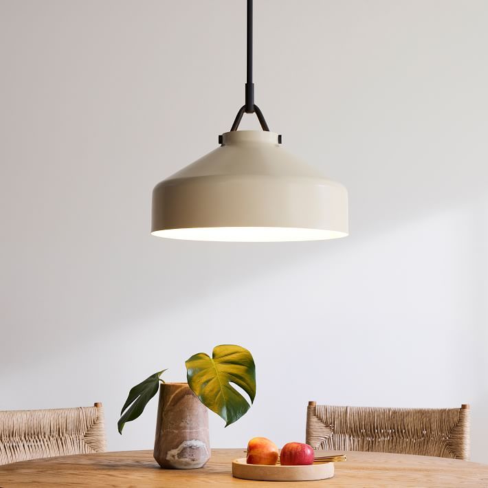 a light hanging over a wooden table with fruit on the plate and bowl next to it