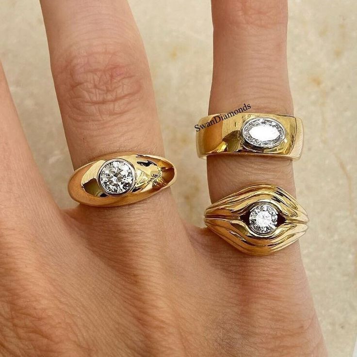 three different rings on someone's hand, one with a diamond in the middle