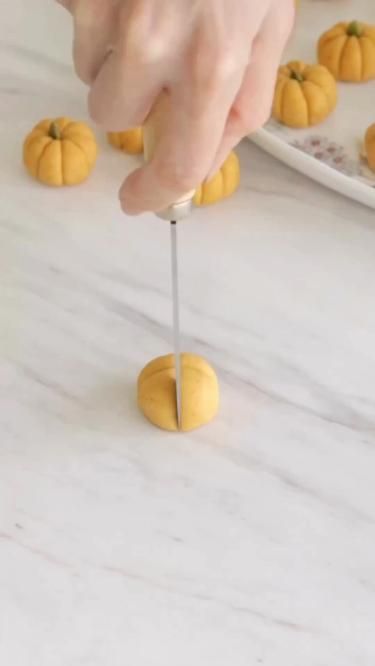 a person is placing miniature pumpkins on top of each other with a toothpick