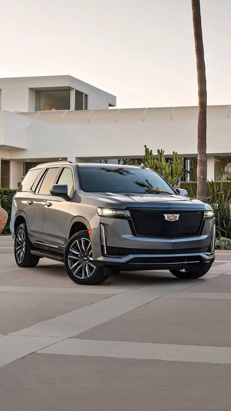 the new cadillac suv is parked in front of a large building with palm trees on it