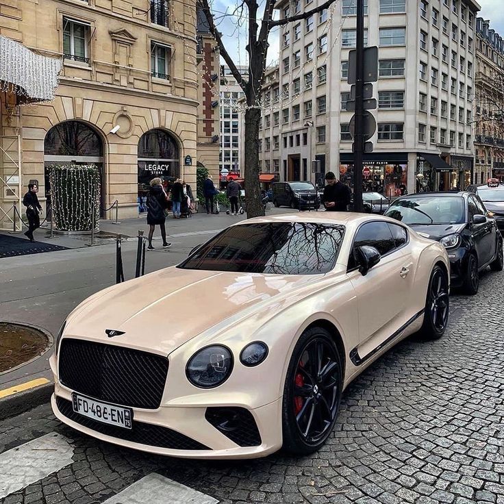 a white car parked on the side of a street next to other cars and people