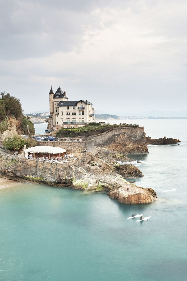 a large house sitting on top of a cliff next to the ocean