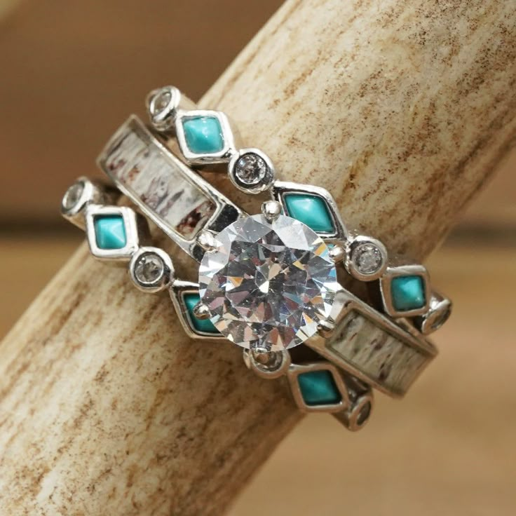 a close up view of a ring on a branch with turquoise stones and diamond accents