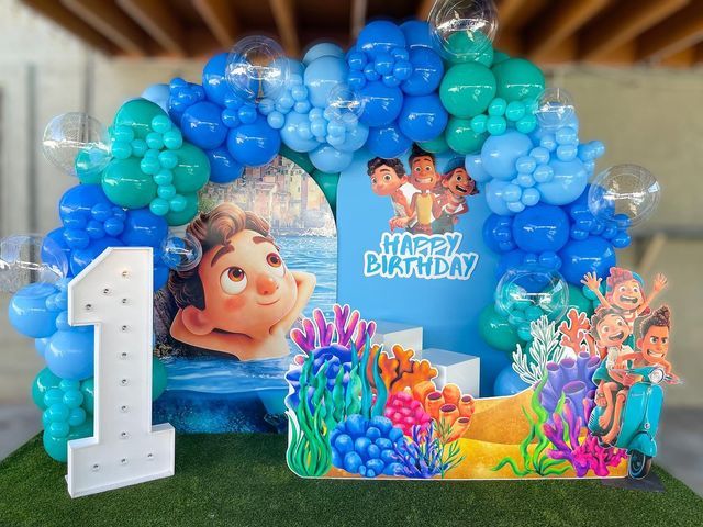 the birthday cake is decorated with blue and green balloons, including an image of cartoon characters