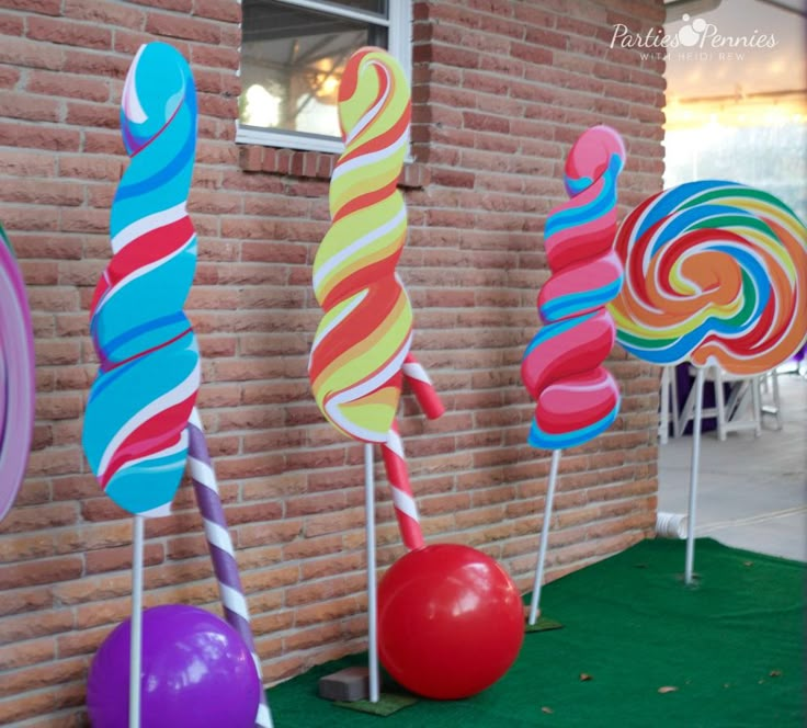 colorful candy lollipops on sticks in front of a brick building