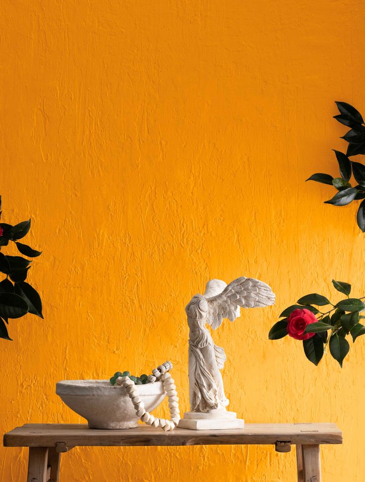 a white statue sitting on top of a wooden table next to a potted plant