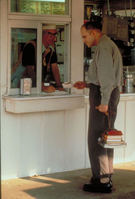 a man standing in front of a store holding a tray with food on top of it