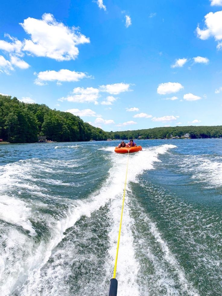 a person on a jet ski being pulled by a boat in the water near some trees