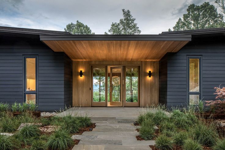 the front entrance to a modern home with wood trimming and stone walkway leading up to it