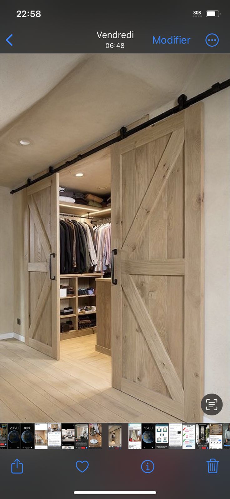 an open barn door in the middle of a room with clothes on hangers and closet doors