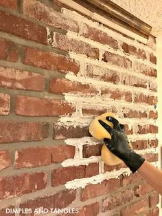 a brick wall with a person wearing black gloves on it's arm and holding a yellow object in the other hand