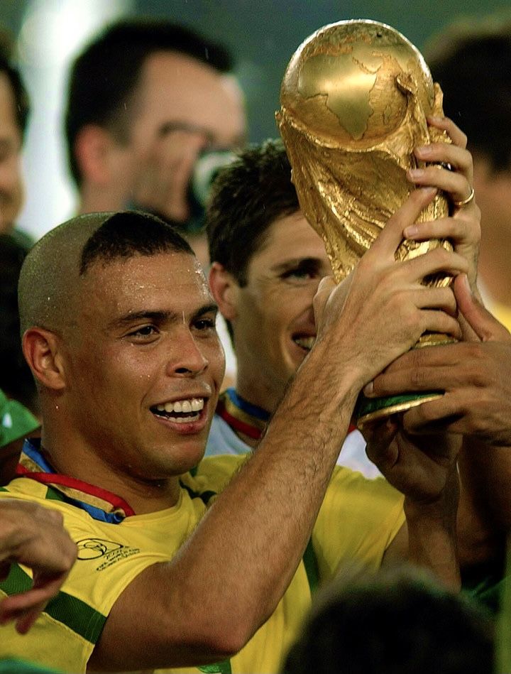 the soccer player is holding up his trophy in front of other players as he smiles