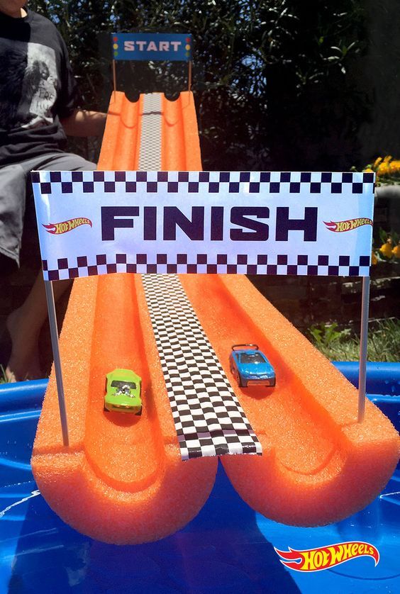 a little boy sitting on top of an inflatable pool with cars and checkered flags