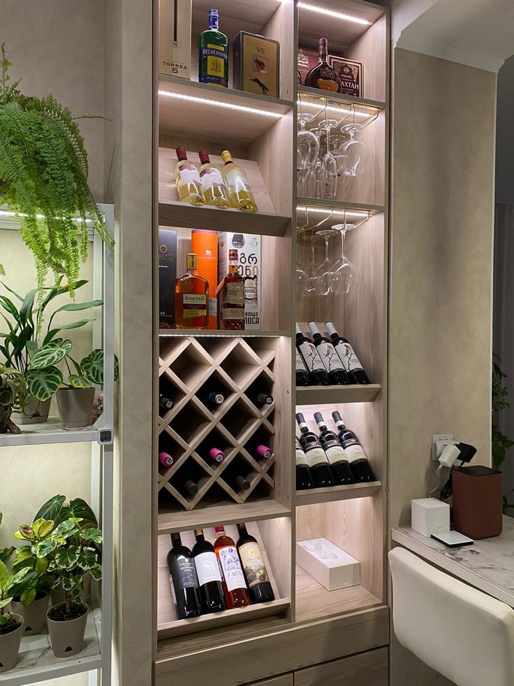 a wine rack filled with lots of bottles and glasses next to a plant in a vase