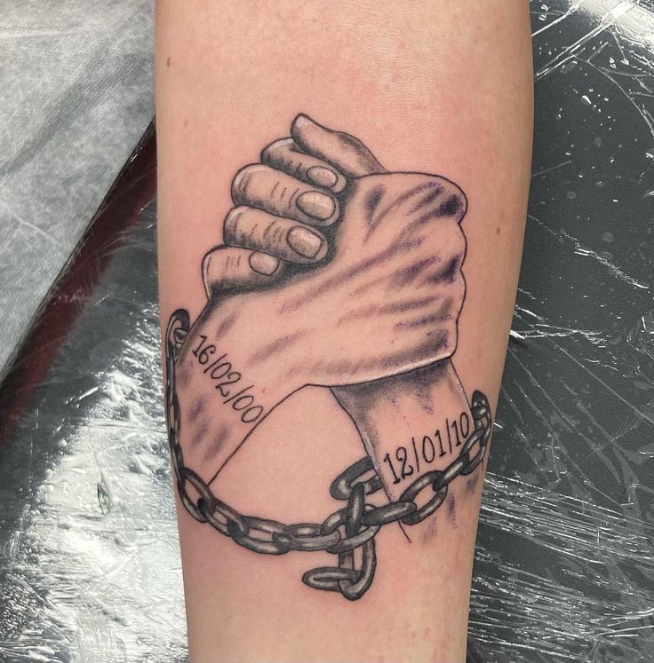 a tattoo on the leg of a person with a chain around his arm and two hands holding