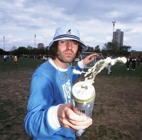 a man in a blue shirt and hat holding a cup with liquid pouring out of it