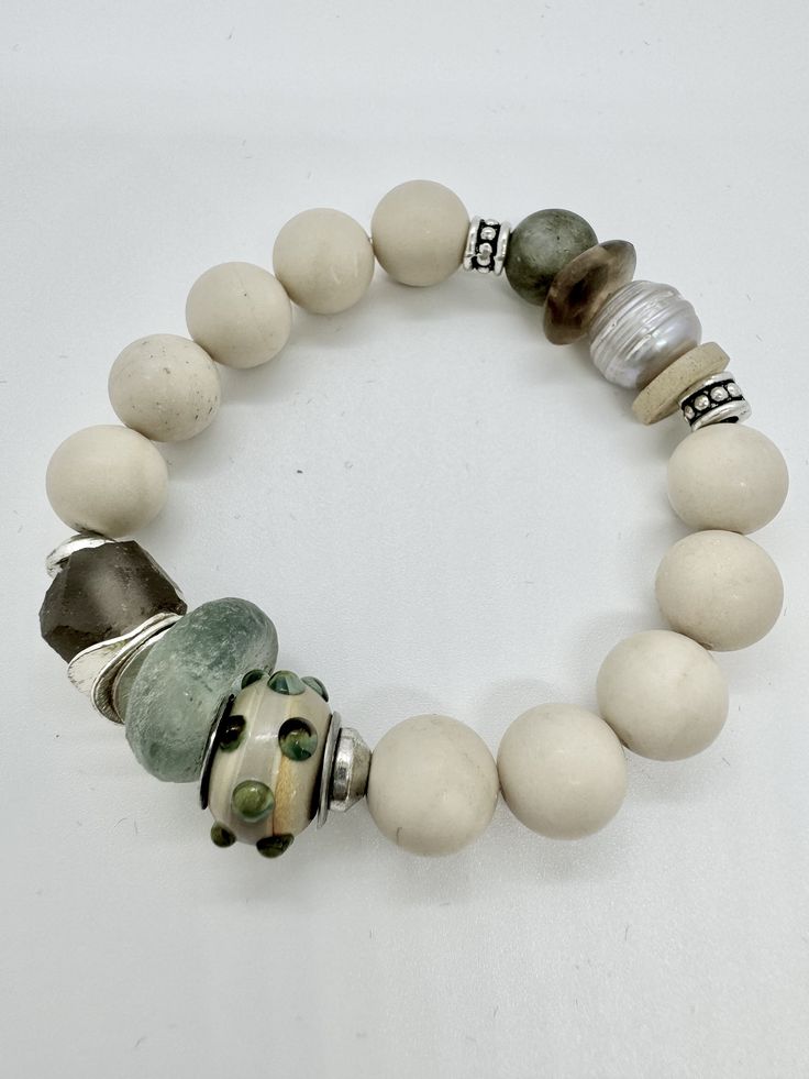 Enhance your accessory collection with the Serenity Sage Artisan Bracelet. Each bead is carefully selected and arranged to create a unique piece that exudes sophistication and natural beauty. This bracelet features: Materials: Matte Agate Beads: Smooth and subtle, these beads add a natural touch to the bracelet. African Glass Beads: Authentic African glass beads bring vibrant textures and colors. Lampwork Bead: A beautifully crafted lampwork bead adds an artistic flair. Pearl Bead: A classic pearl that offers timeless elegance. Raw Crystal Nugget: Natural and raw, it adds an earthy charm to the bracelet. Silver Accents: Polished silver elements enhance the overall design with a touch of shine. Features: Handcrafted Quality: Each bracelet is meticulously handmade, ensuring a unique and high Bohemian Rondelle Bracelets With Polished Beads, Spiritual Jade Beaded Bracelets With Spacer Beads, Handmade Jade Bracelets For Everyday Wear, Artisan Beaded Bracelets For Meditation, Earthy Agate Beaded Bracelets With Natural Stones, Earthy Beaded Bracelets With Natural Agate Stones, Adjustable Jade Pearl Bracelet With Round Beads, Unique Everyday Jewelry With Large Beads, Everyday Agate Hand-strung Bracelets