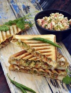 a cut in half sandwich sitting on top of a cutting board next to a bowl of salad