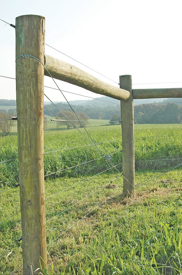 a wooden fence in the middle of a grassy field