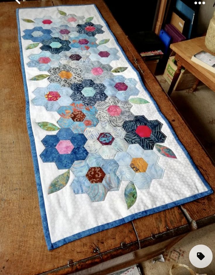 a table with a quilt on it that has been made into a flower pattern and is sitting on top of a wooden table