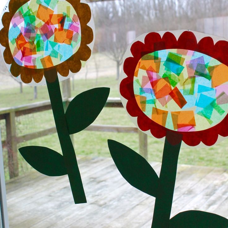 two paper flowers sitting on top of a window sill next to a wooden deck