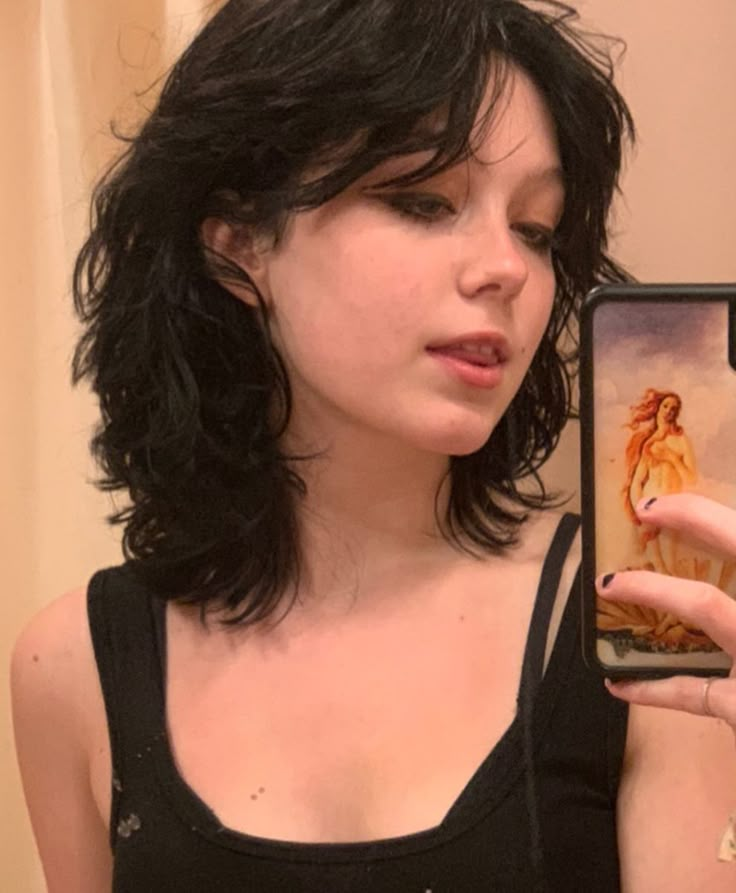 a woman taking a selfie with her cell phone in front of her face while wearing a black tank top