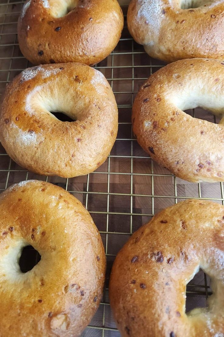 six bagels sitting on a cooling rack ready to be baked in the oven,