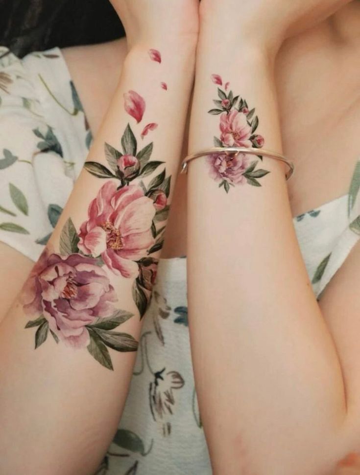 two women with matching tattoos on their arms, one holding the other's hand